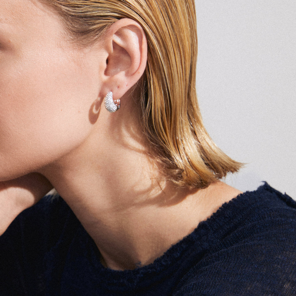 Plusieurs boucles d’oreilles argentées portées