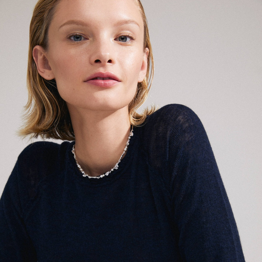 Collier argenté porté avec un chandail bleu marine