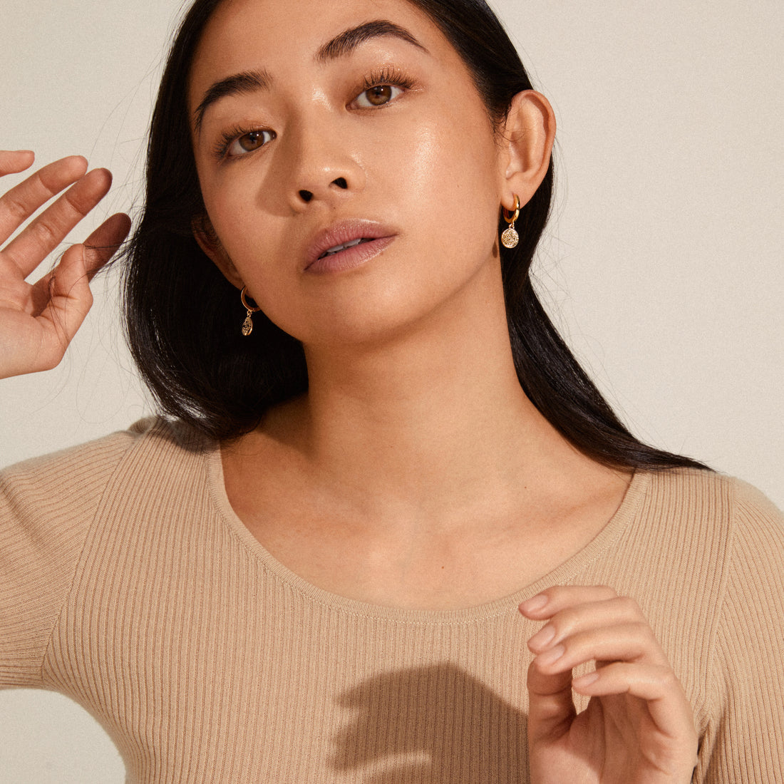 Boucles d’oreilles pendantes portées avec un haut beige