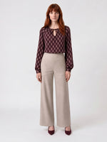 Blouse Isabella en viscose avec imprimé géométrique bordeau et.detail nœud col, associée à un pantalon beige ample.