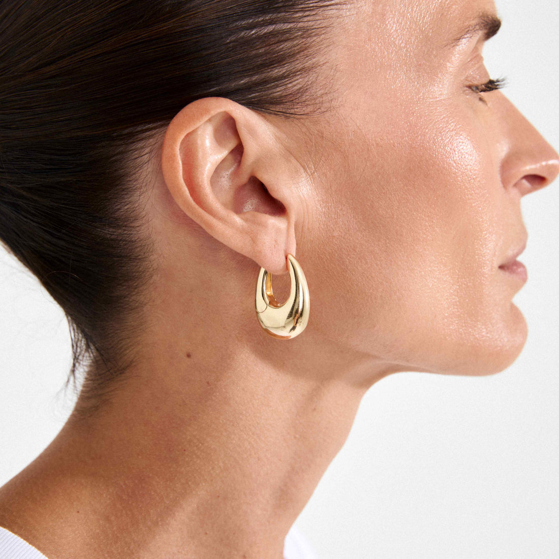 Boucle d’oreille dorée en goutte portée, vue de profil