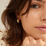 Petite boucle d’oreille dorée arrondie portée
