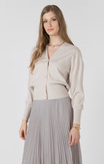 Cardigan beige porté avec une jupe plissée