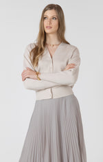 Cardigan beige porté, bras croisés