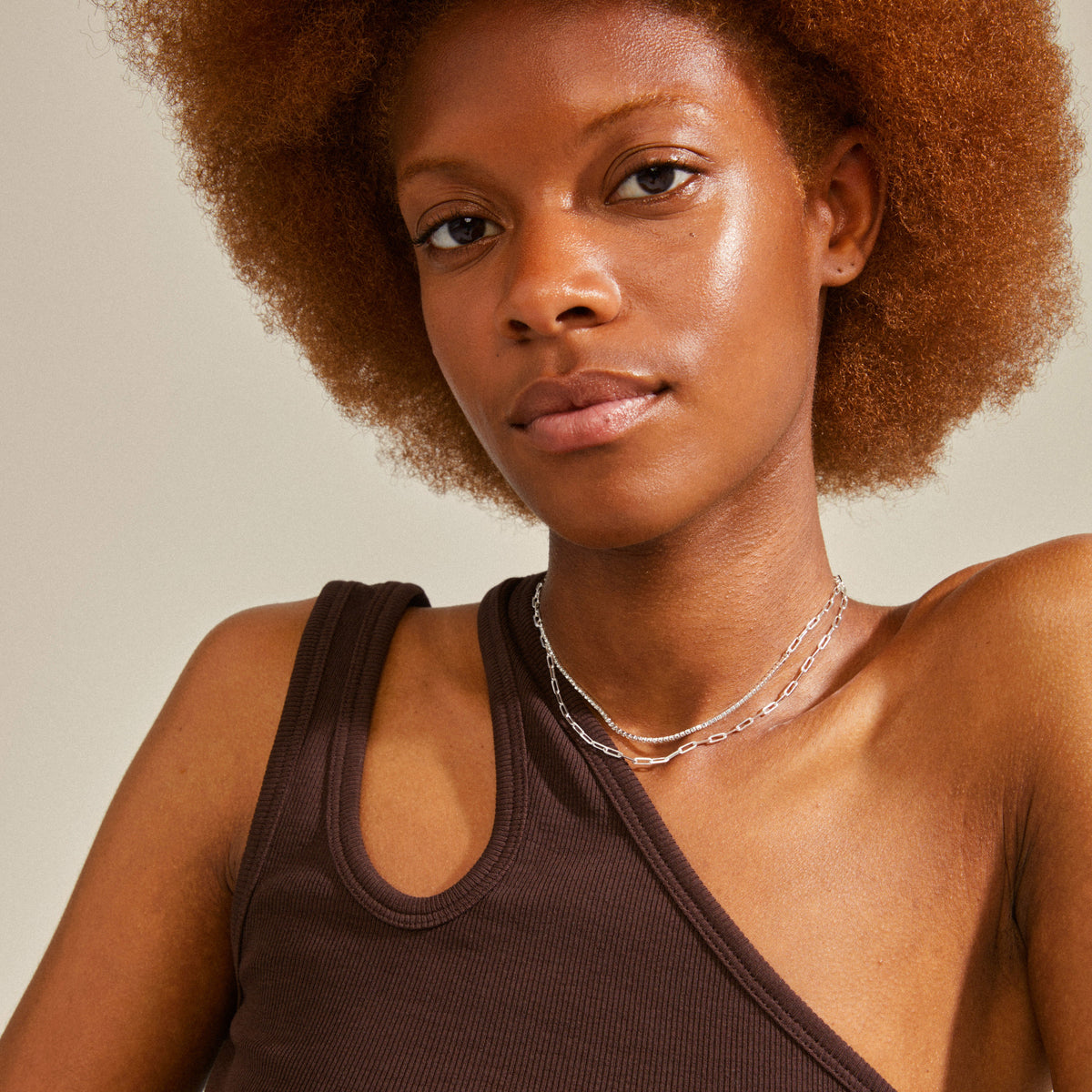 Collier argenté à deux chaînes porté avec un haut brun