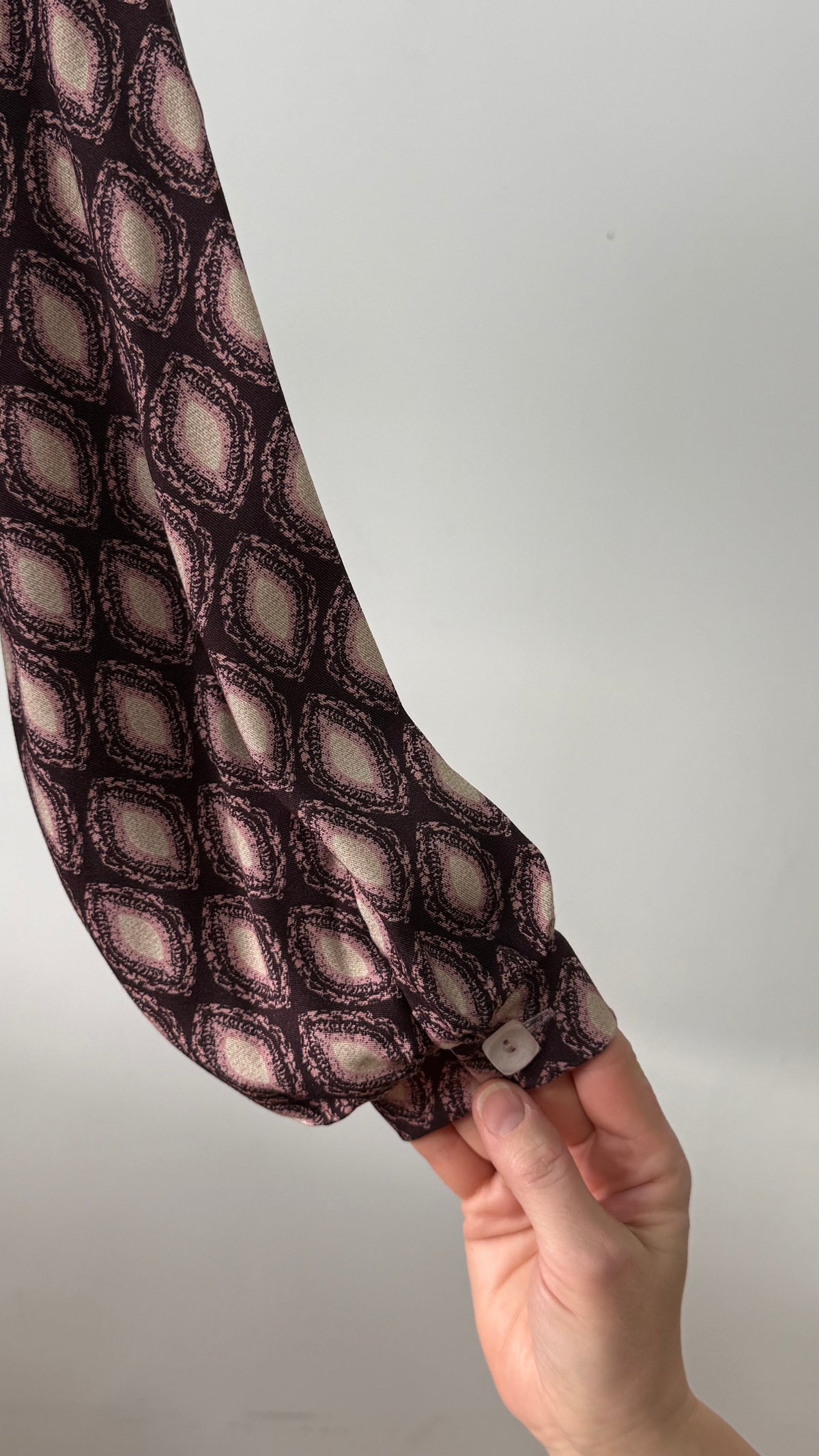 Détail du poignet de la blouse Isabella en viscose, ornée d'un imprimé géométrique aux teintes prune et rose avec boutons discrets.