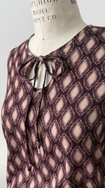 Blouse Isabella en viscose à imprimé géométrique marron et rosé, avec col rond et nouet délicat.