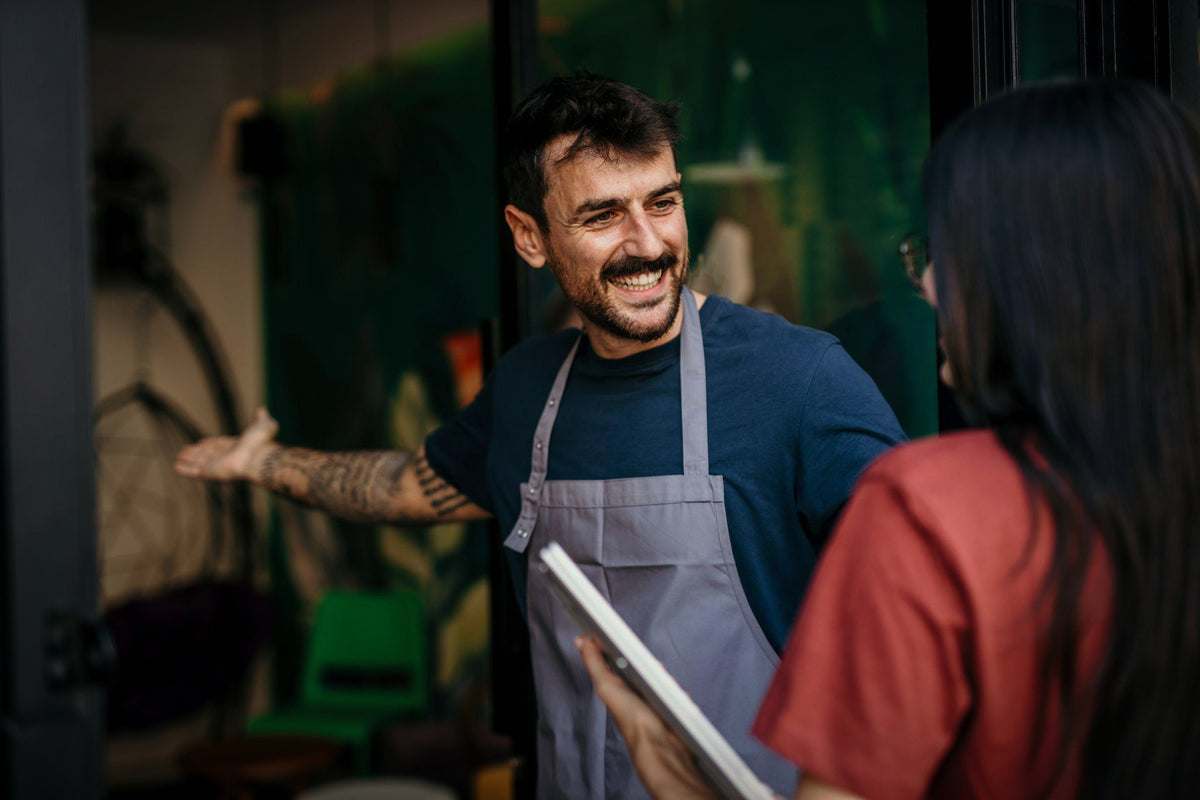 Commerçant en tablier accueillant une cliente