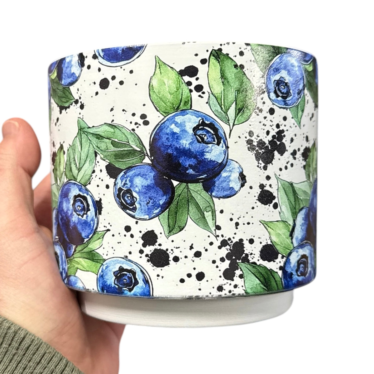 Tasse blanche à motif de bleuets tenue dans une main
