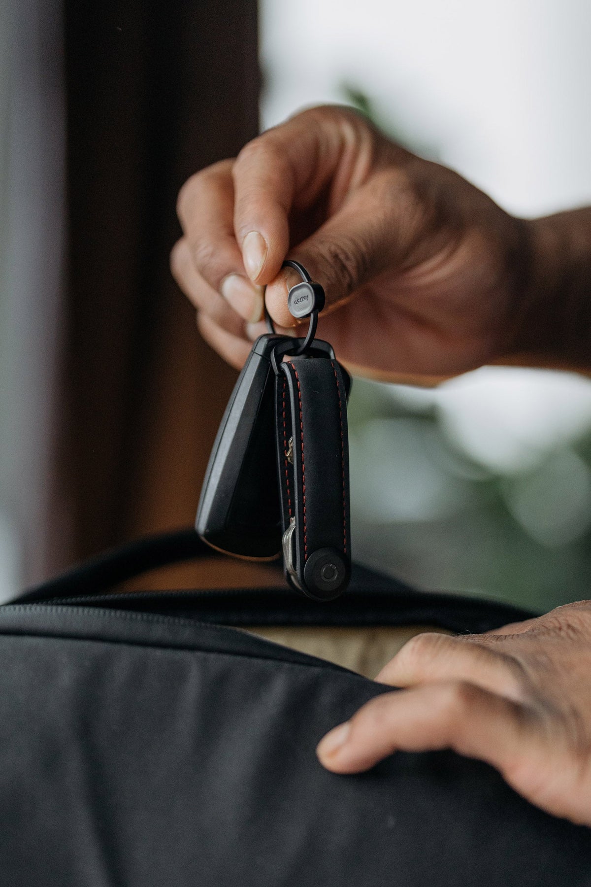 Anneau porte-clés à ouverture rapide Orbitkey Ring v2 — trousseau tenu au-dessus d’un sac