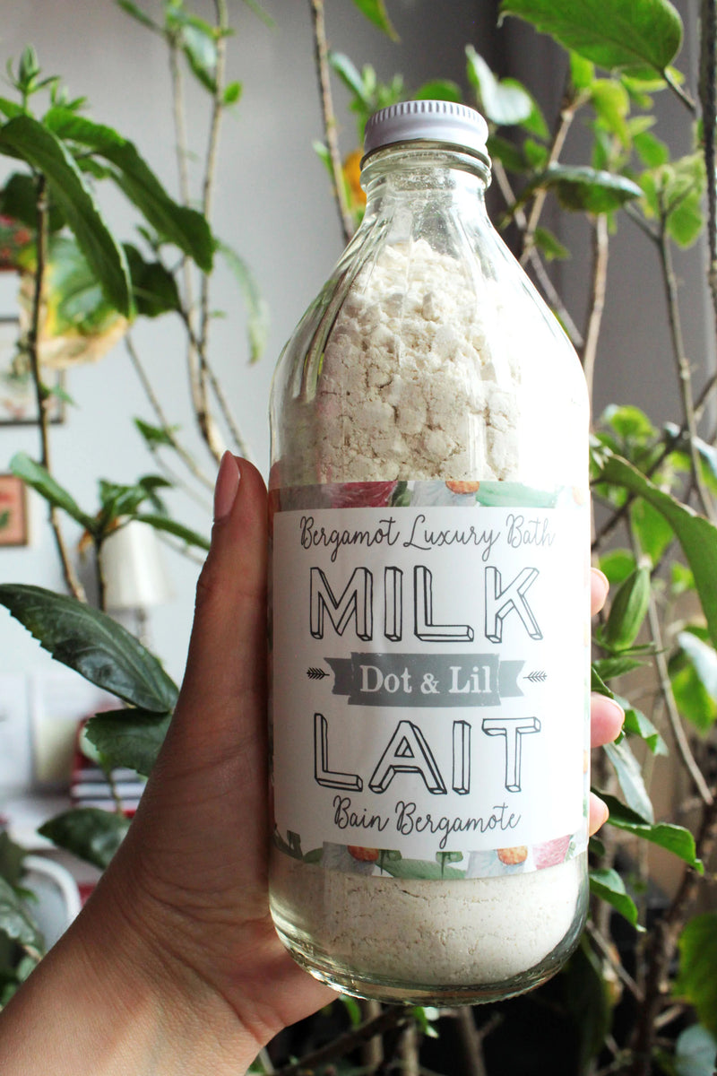 Bouteille de lait de bain à la bergamote tenue dans une main