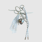 Breloque de sac – Cœur argenté et dentelle. Cœur argenté, dentelle blanche, perles décoratives et cordons blancs à touches noires.