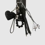 Breloque de sac – Cœur léopard noir. Cœur à motif léopard noir et gris, perles décoratives, franges noires et petites étoiles argentées.