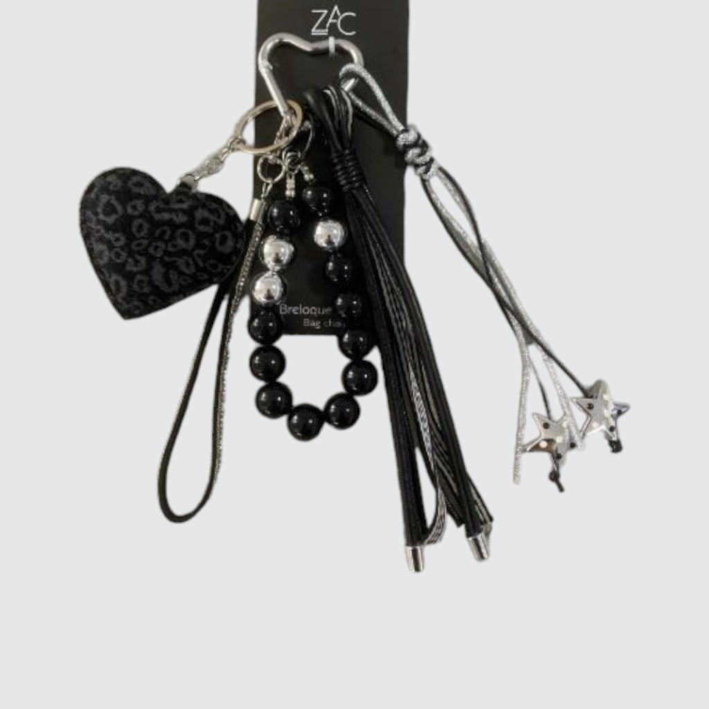 Breloque de sac – Cœur léopard noir. Cœur à motif léopard noir et gris, perles décoratives, franges noires et petites étoiles argentées.