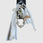 Breloque de sac – Lapin blanc. Lapin blanc à petit nœud beige, perles décoratives ornées d’étoiles dorées, rubans et dentelle.
