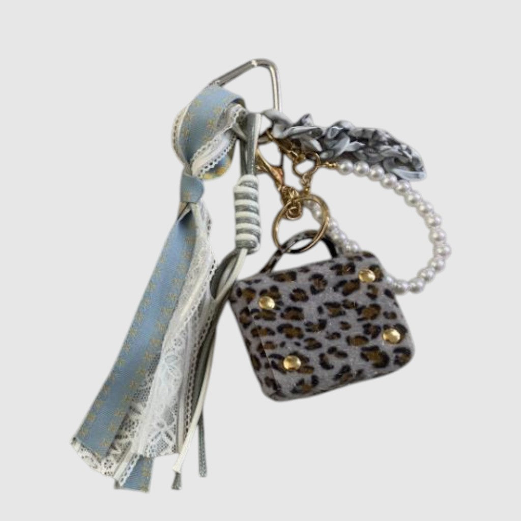 Breloque de sac – Mini-sac léopard gris. Mini-sac décoratif à motif léopard gris, rubans bleu pâle, dentelle et perles décoratives.