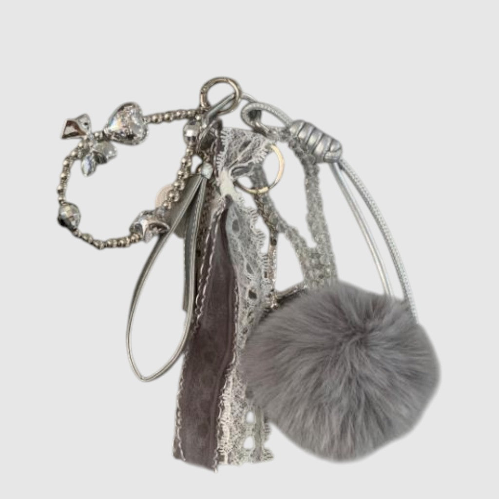 Breloque de sac – Pompon gris. Pompon gris, rubans, dentelle et détails argentés composent cette breloque aux textures variées.