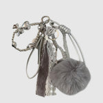 Breloque de sac – Pompon gris. Pompon gris, rubans, dentelle et détails argentés composent cette breloque aux textures variées.
