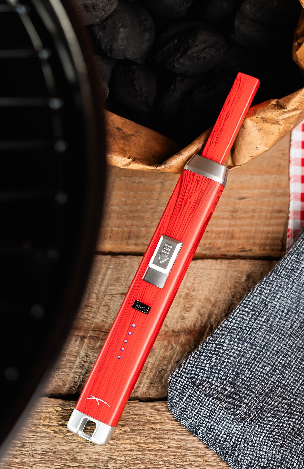 Briquet Sizzle Pitmaster rouge près d’un barbecue
