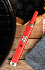 Briquet Sizzle Pitmaster rouge près d’un barbecue