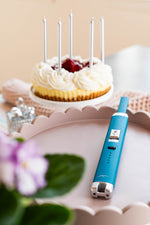 Briquet Sizzle Pitmaster turquoise près d’un gâteau