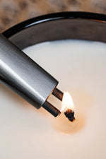 Briquet Sizzle Sleek allumant la mèche d’une chandelle