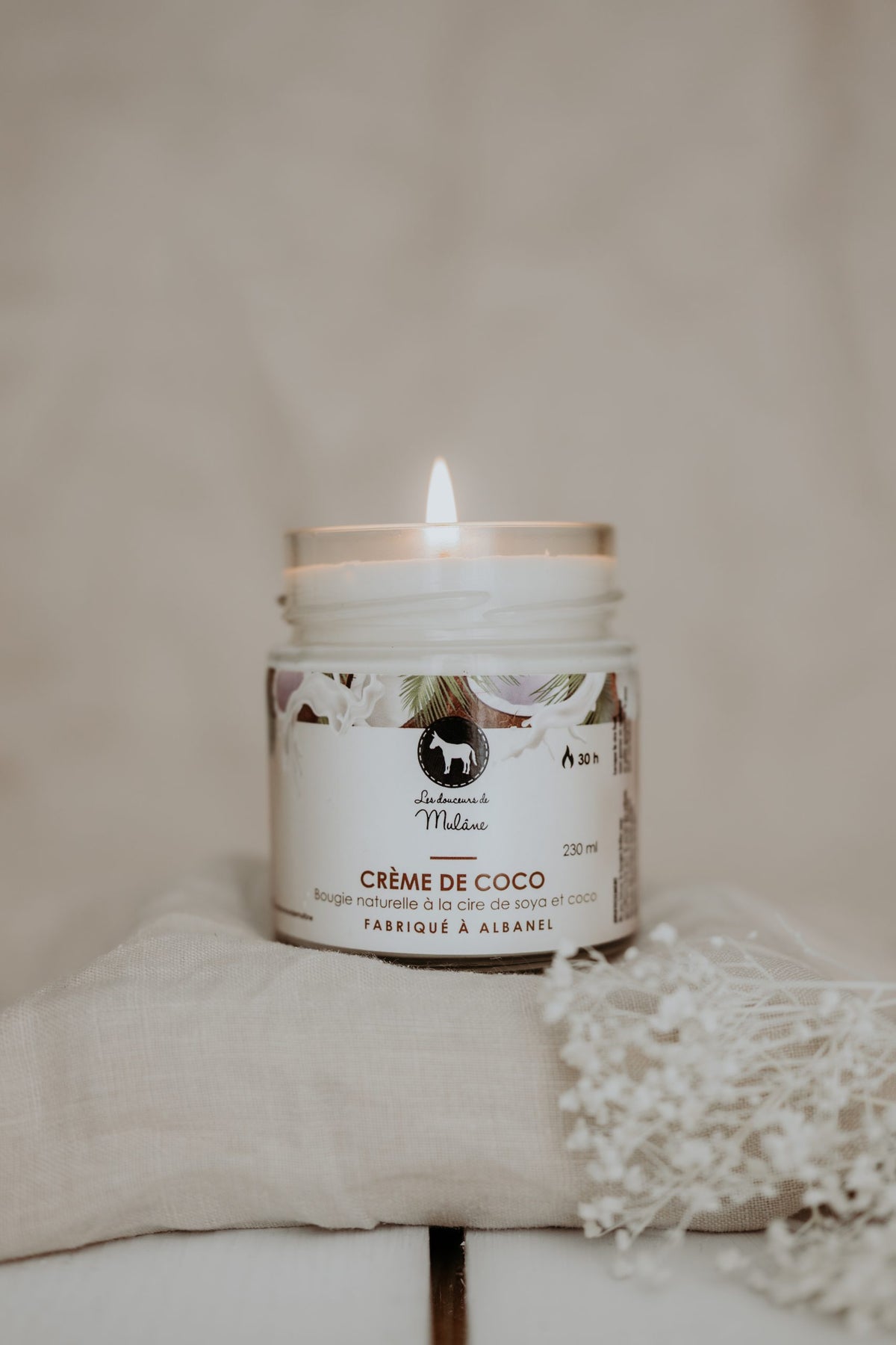 Bougie crème de coco Mulâne allumée dans un pot de verre