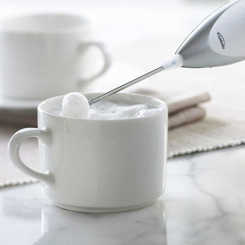 Fouet du mousseur Trudeau au-dessus d’une tasse de lait mousseux