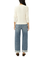 Back view of a model wearing Maison Taïga mid-rise relaxed straight-leg jeans in indigo denim with cuffed hems.
