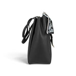 Sac à main Maison Taïga Évasion noir en PVC avec texture grainée et détail de foulard imprimé, vue de profil.