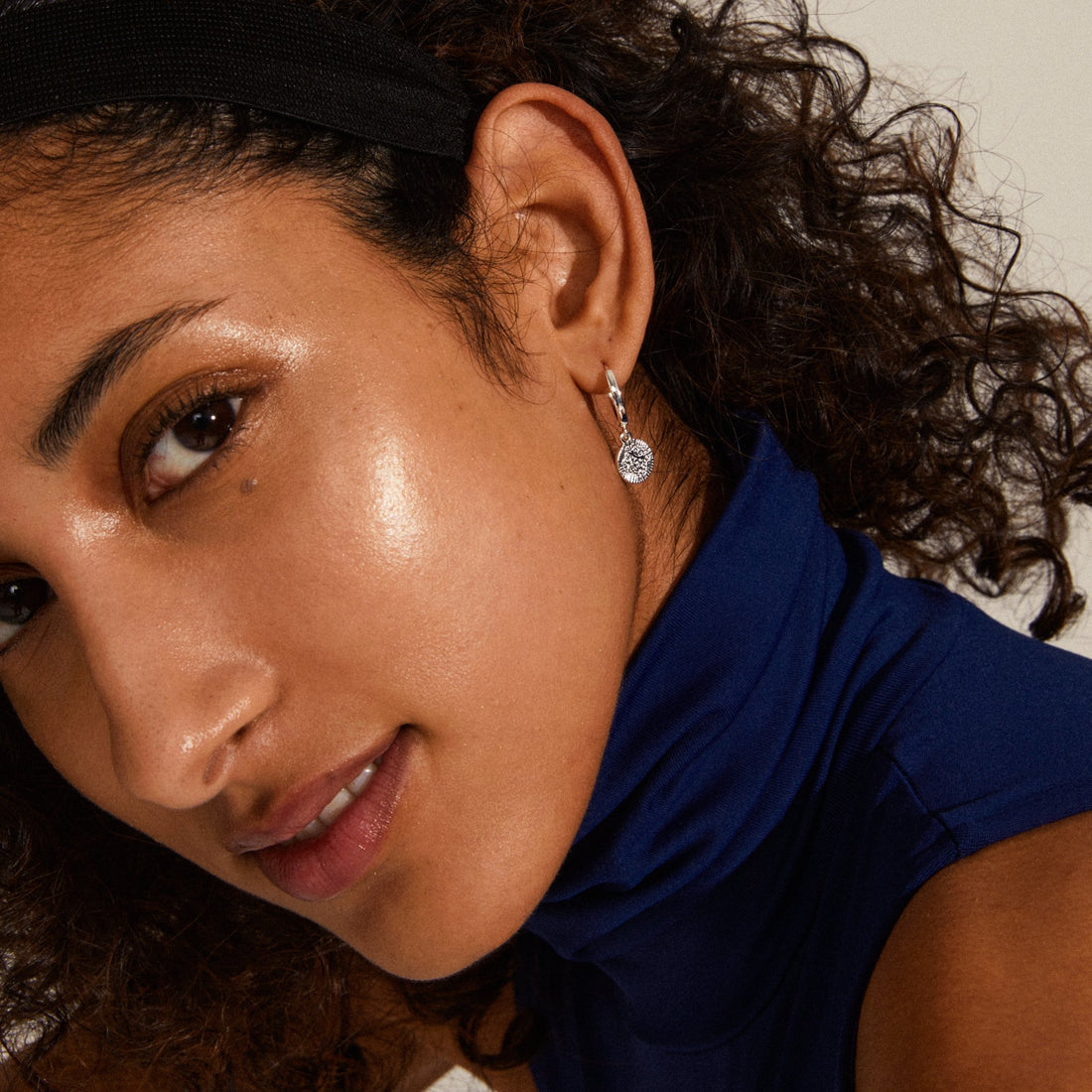 Boucle d’oreille pendante argentée portée avec un haut bleu