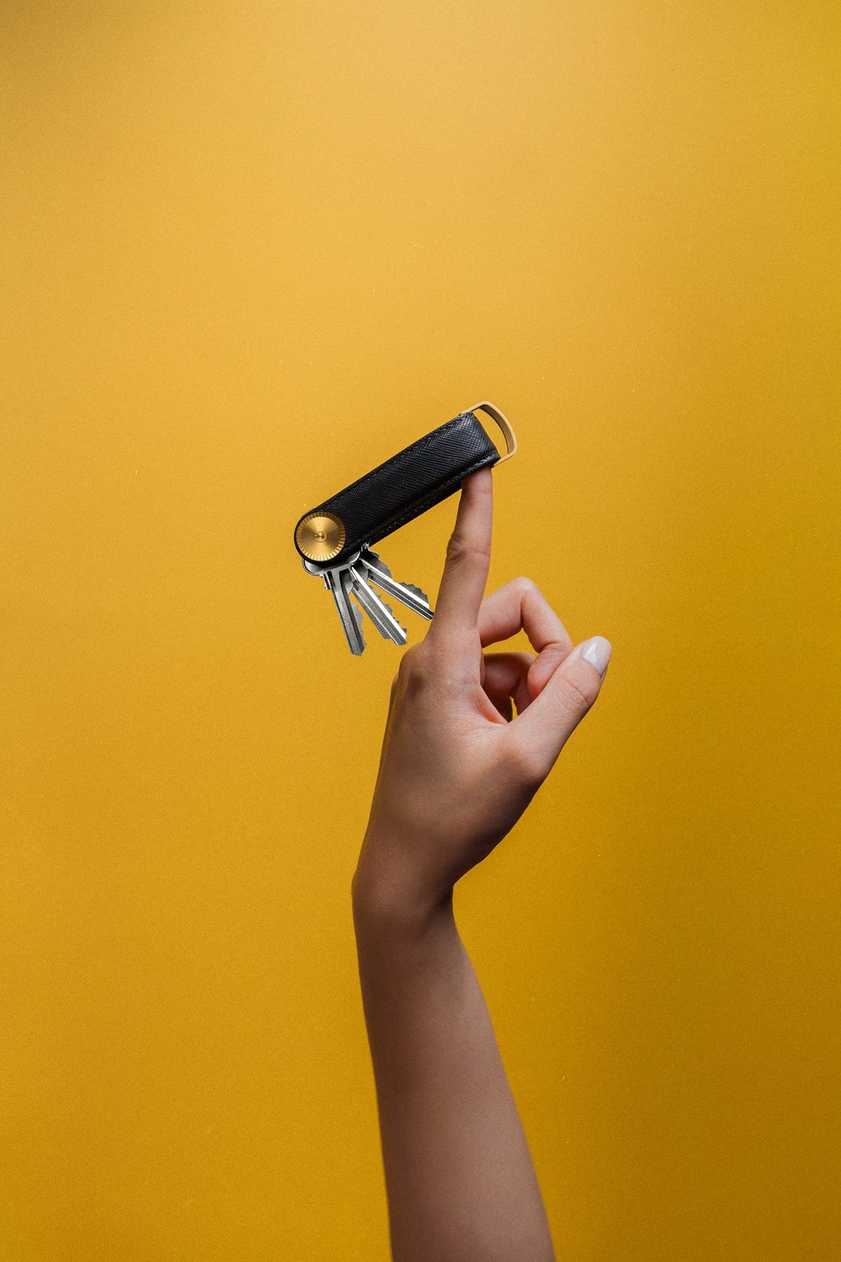 Organiseur de clés Pro en cuir Saffiano Orbitkey — organiseur noir présenté en main sur fond jaune