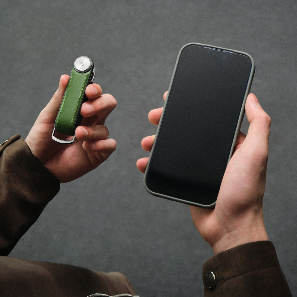 Organiseur de clés Tracker en cuir Orbitkey — organiseur vert et téléphone tenus en main