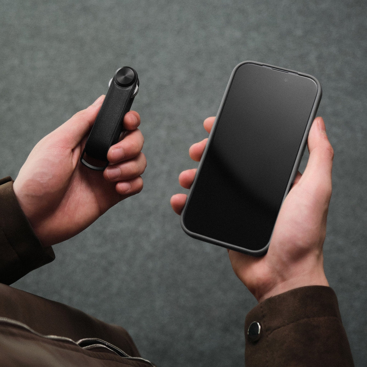 Organiseur de clés Tracker sans cuir Orbitkey — organiseur noir et téléphone tenus en main